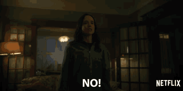 a woman standing in a living room with the words " no " on her face