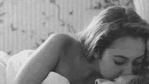 a black and white photo of two women kissing each other .