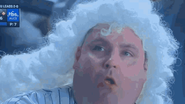 a man wearing a white wig is watching a baseball game and the score is 6-2