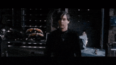 a man is standing in front of a large explosion in a dark room .