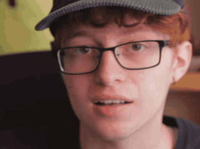 a man wearing glasses and a hat is looking at the camera