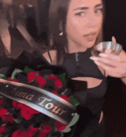 a woman is holding a bouquet of red roses with a banner that says alma tour