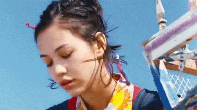 a close up of a woman 's face with a blue sky in the background