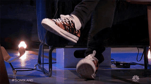 a person sitting on a couch with their feet up and a nbc logo in the background