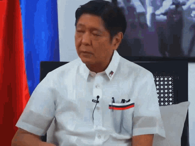 a man in a white shirt has a pen in his pocket with a red white and blue flag on it