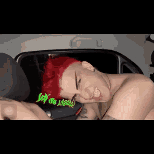 a shirtless man with red hair is laying in the back seat of a car .