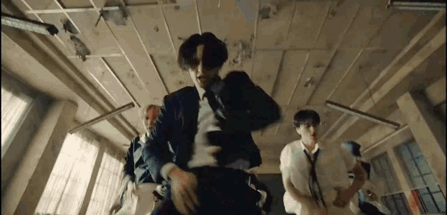a group of young men are dancing in a room in a suit and tie .