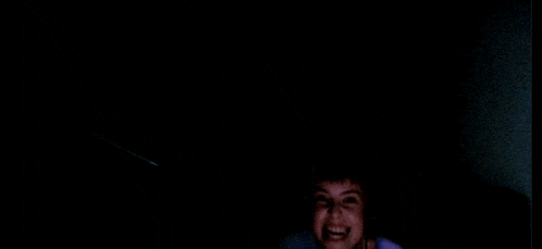 a young boy is smiling in the dark with a purple shirt on