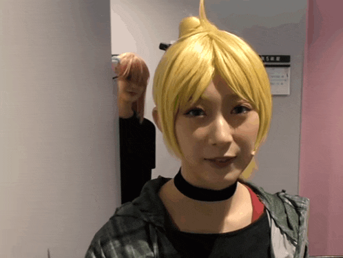 a woman wearing a yellow wig and a choker stands in front of a sign that says ' emergency exit '