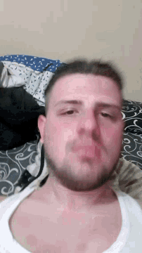 a man with a beard is laying on a bed and looking at the camera