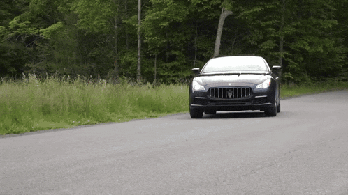 a black maserati car is driving down a road