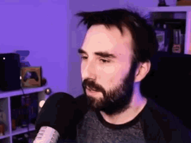 a man with a beard is standing in front of a microphone .