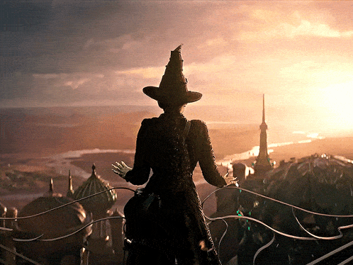 a woman wearing a witch hat stands on a balcony overlooking a city