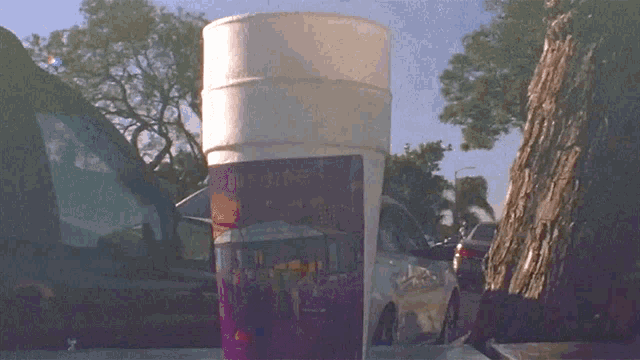 a white cup with a purple label that says soft drinks on it