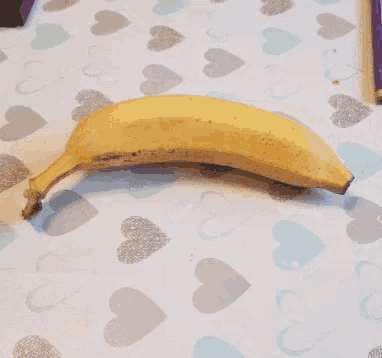 a peeled banana is laying on a heart patterned table cloth