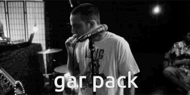 a black and white photo of a man singing into a microphone with the word gar pack below him