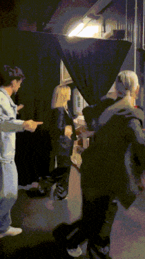 a group of people are standing in front of a black curtain and a sign that says ' a '