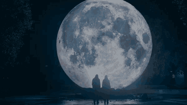 two people standing in front of a large full moon