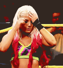 a woman in a wrestling ring holds her hand to her face