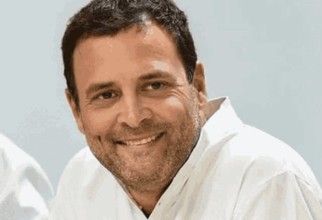 a man with a beard and a white shirt is smiling .