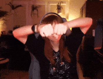a woman wearing headphones and a black shirt is making a fist gesture