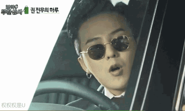 a man wearing sunglasses is driving a car with chinese writing on the screen