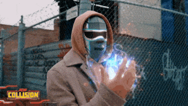 a man in a hooded jacket stands in front of a chain link fence with the words new collision on the bottom right