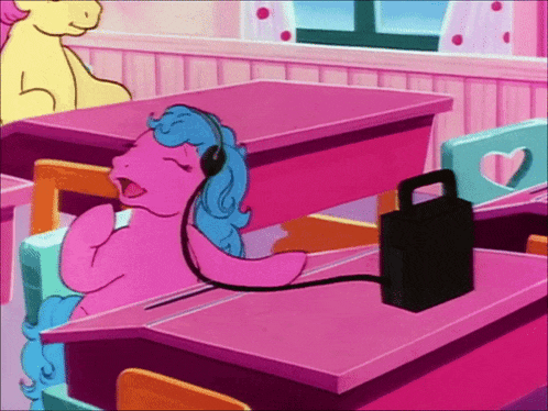 a pink pony wearing headphones is sitting at a desk