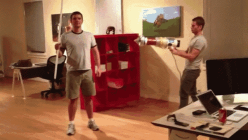 two men are standing in a room with a red shelf and a painting on the wall