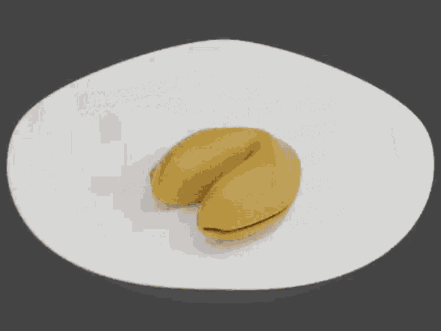 a fortune cookie is sitting on a white plate with a small figure sticking out of it .