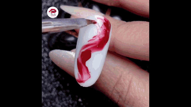 a close up of a person 's nails with a red swirl