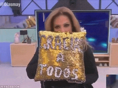 a woman holds a pillow that says gracias a todos