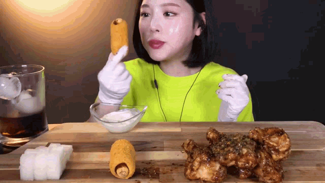a woman in a yellow shirt and white gloves is eating chicken