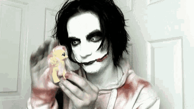 a man in a joker costume is holding a small toy pony .