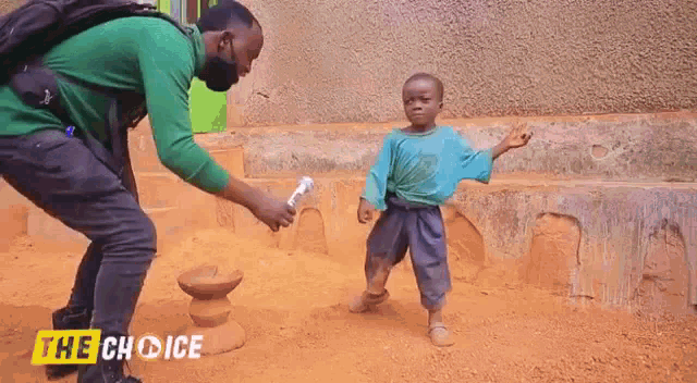 a man in a green shirt is standing next to a little boy in a blue shirt and holding a bottle of water .