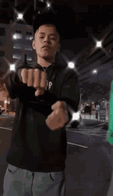 a man wearing a black shirt and a green hoodie is standing in front of a building .