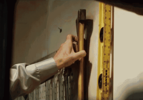 a man is holding a hammer next to a yellow ruler that says maven on it