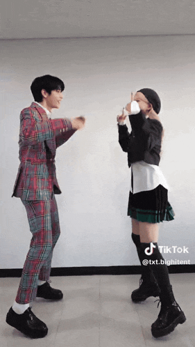 a man in a plaid suit and a woman in a green skirt are dancing together on tiktok .
