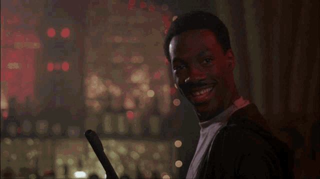a man is smiling and holding a bat in his hand
