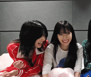 a group of young women are laughing and smiling while sitting on a bed