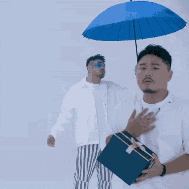 a man holding a blue umbrella and a gift box