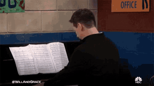 a man plays a piano in front of a sign that says office