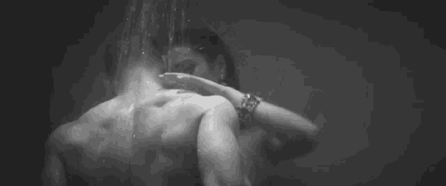 a black and white photo of a man and a woman kissing under a shower .