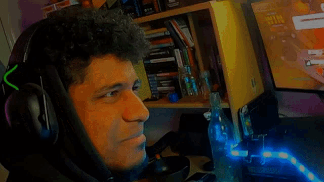 a man wearing headphones looks at a computer screen which shows the time as 10:13
