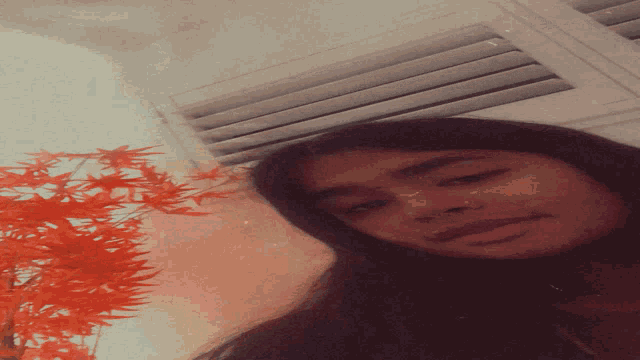 a woman is laying down with her head on a ceiling vent