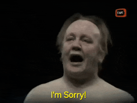 a man without a shirt is saying i 'm sorry in a dark room .