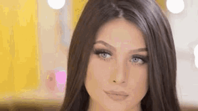 a woman with long brown hair and blue eyes is making a funny face .