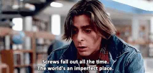 a man in a denim jacket is sitting in a library with a quote .