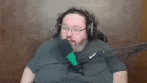 a man with a beard is sitting in front of a microphone wearing headphones .