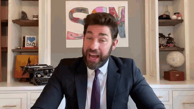 a man in a suit and tie is talking in front of a sign that says sn